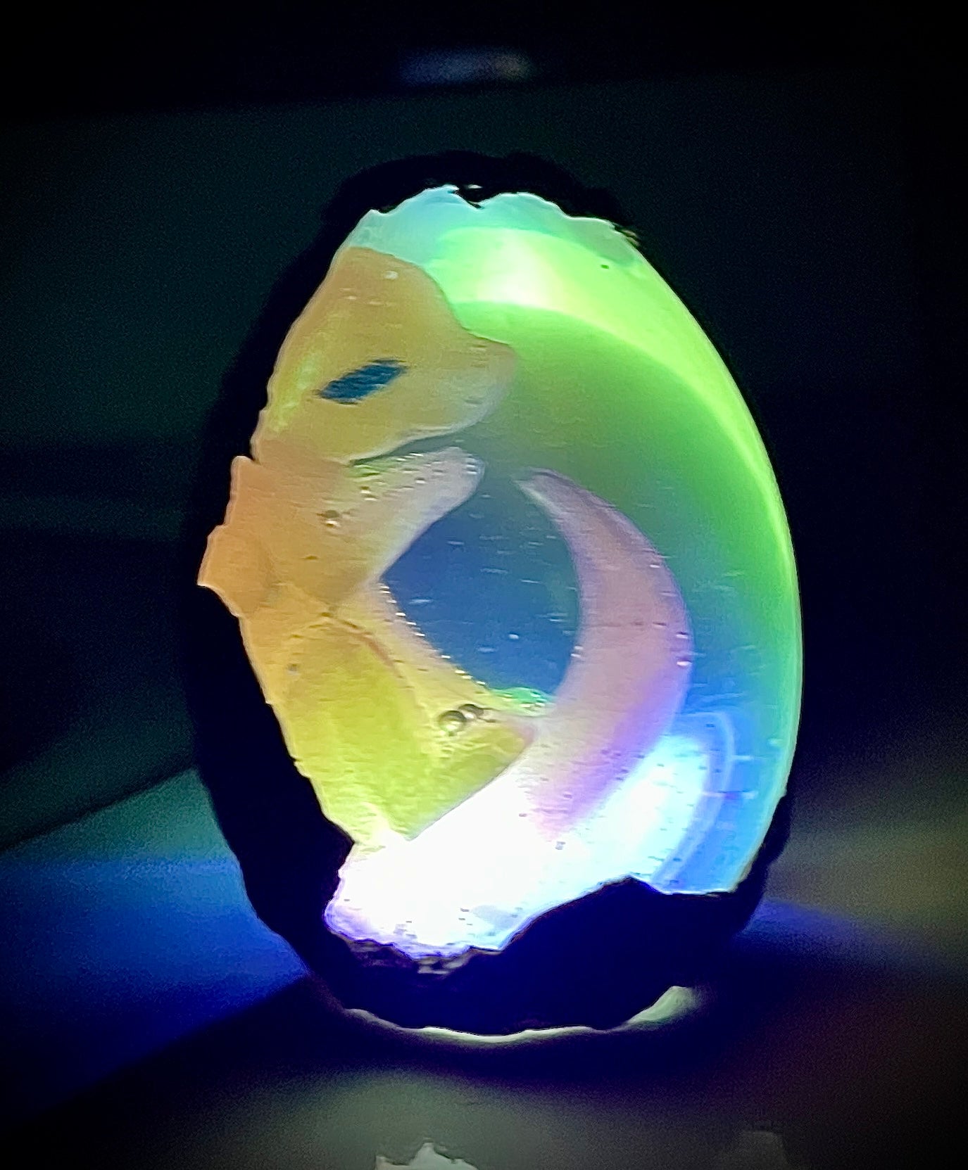 Glowing multicolored stone with a dragon design on a dark background