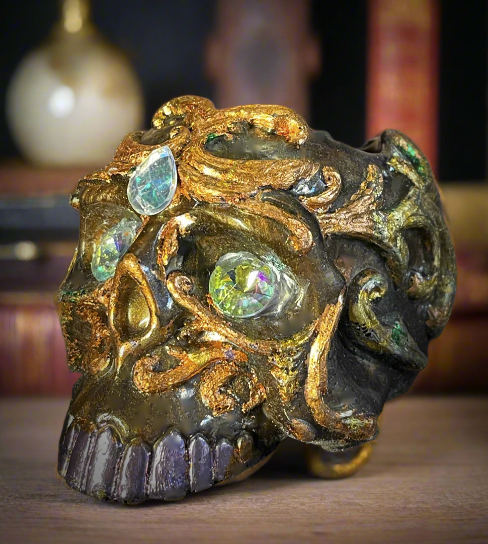 Decorative skull with gold and green gemstones on a dark background
