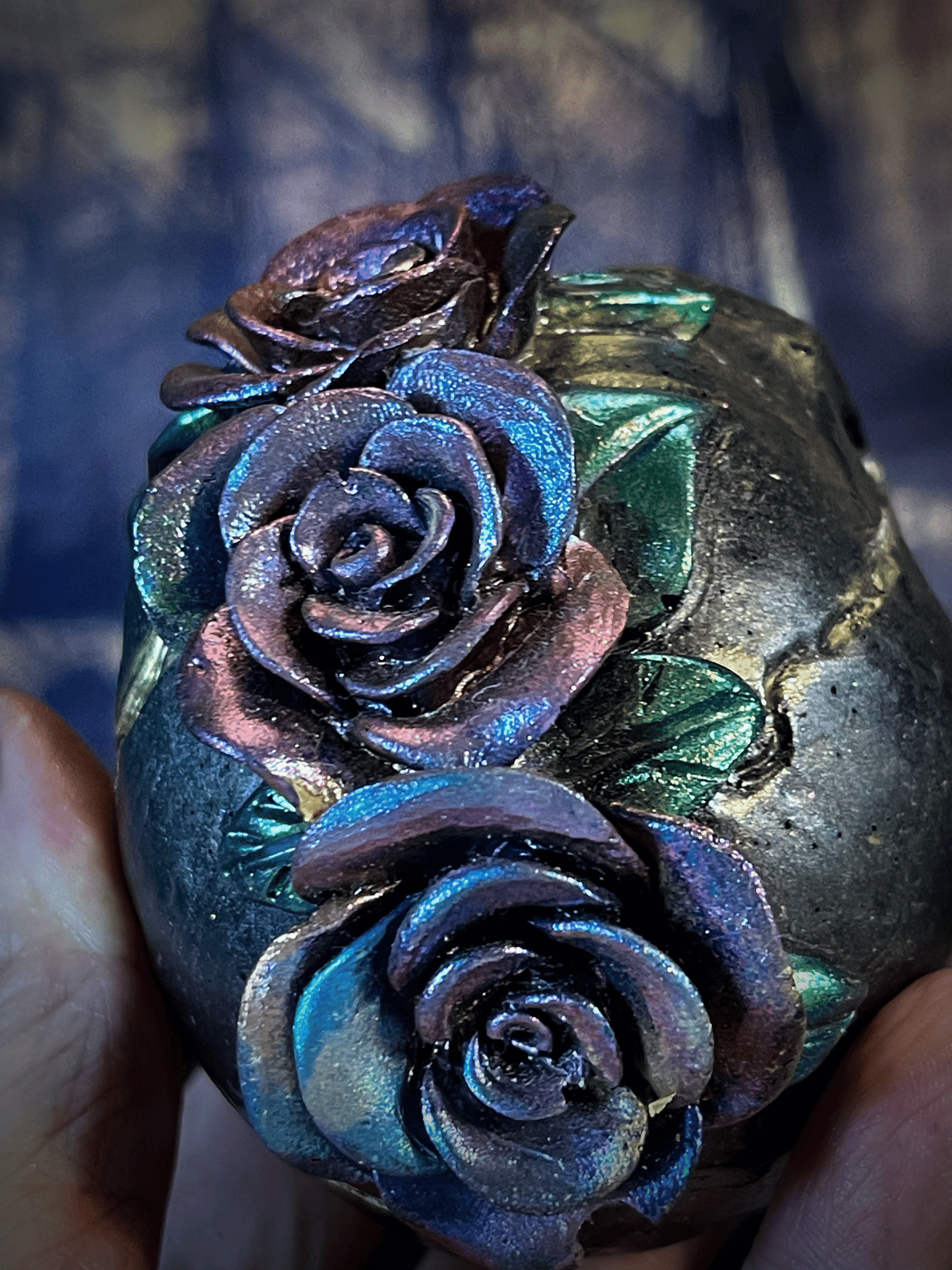 Decorative stone with embossed roses held in a hand against a blurred background
