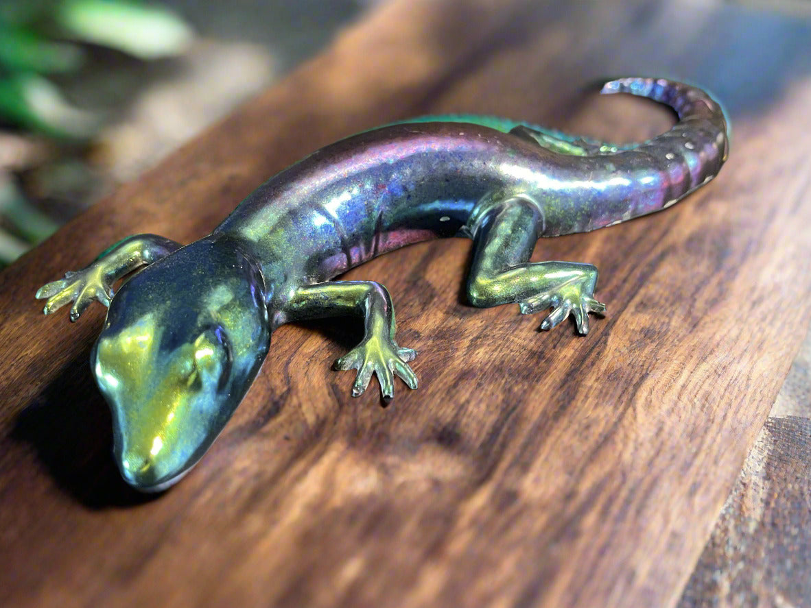 Metallic lizard figurine on a reflective surface