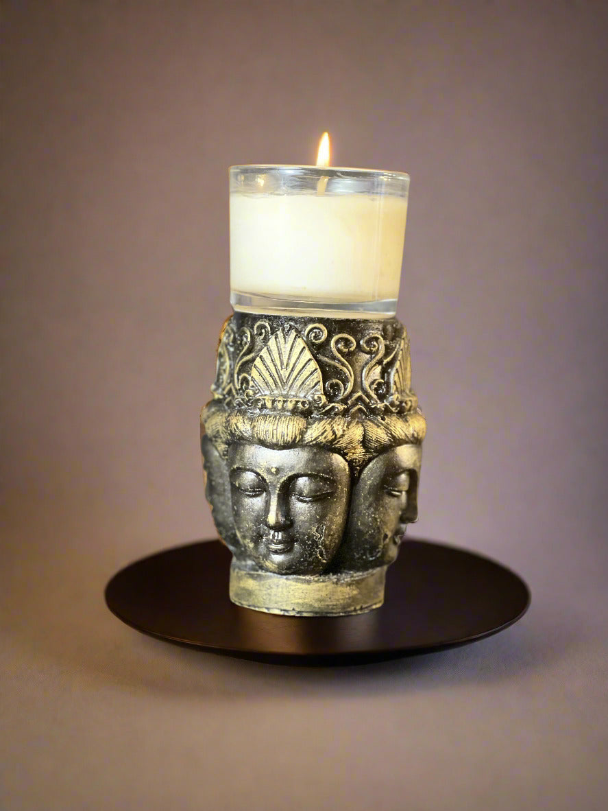 Decorative candle holder with three faces on a dark surface