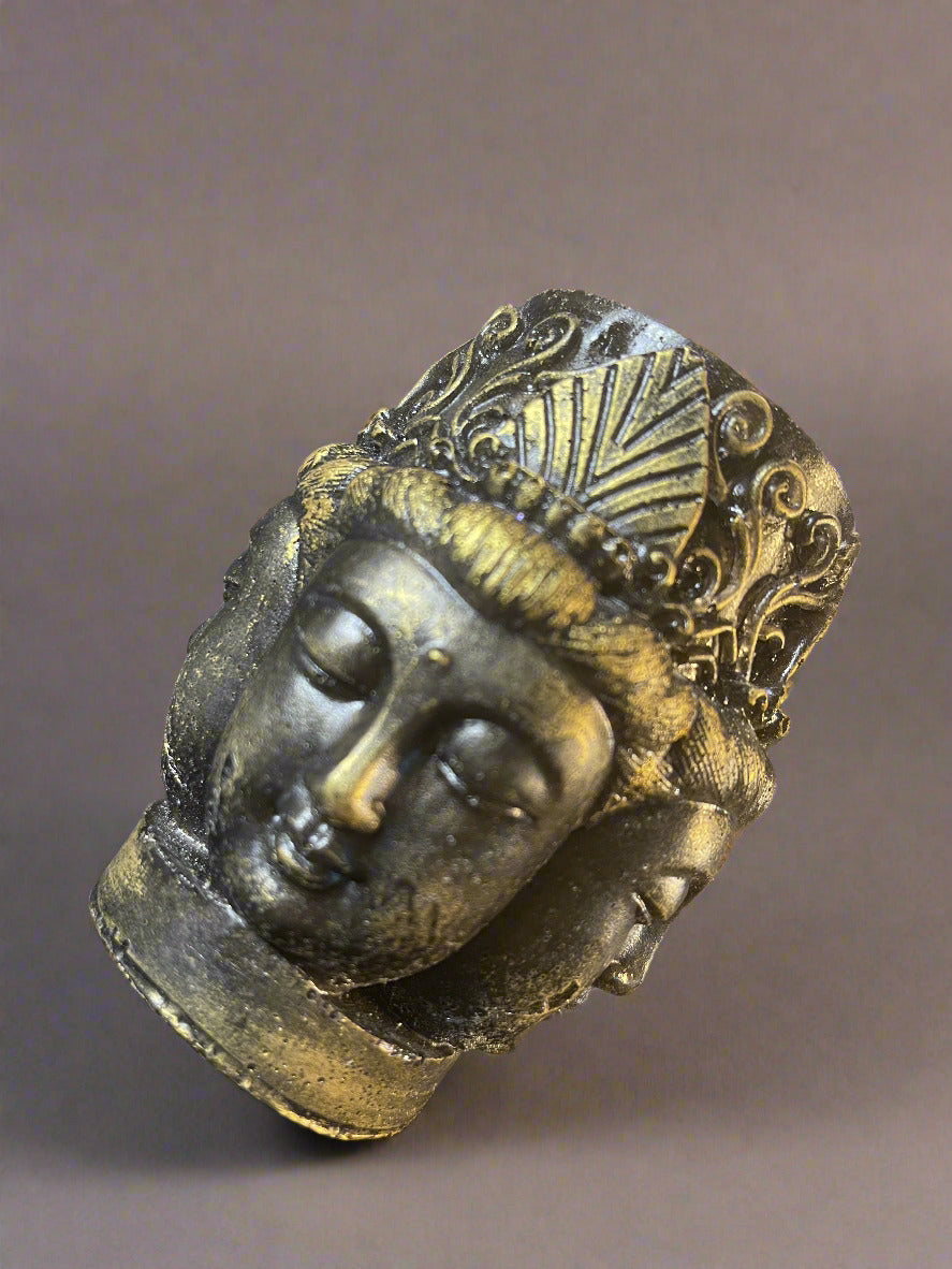 Decorative buddha head with intricate designs on a reflective surface