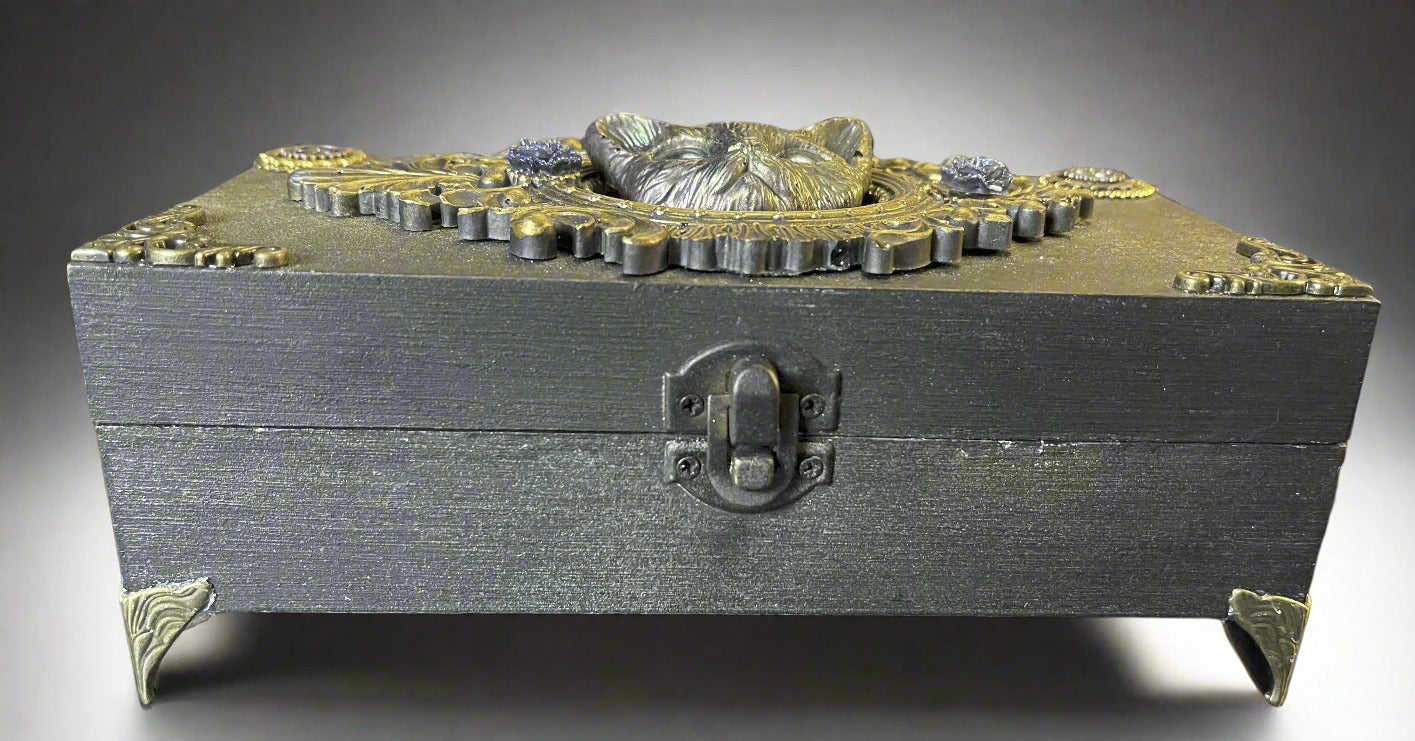 Decorative wooden box with intricate designs and a lock on a dark surface.