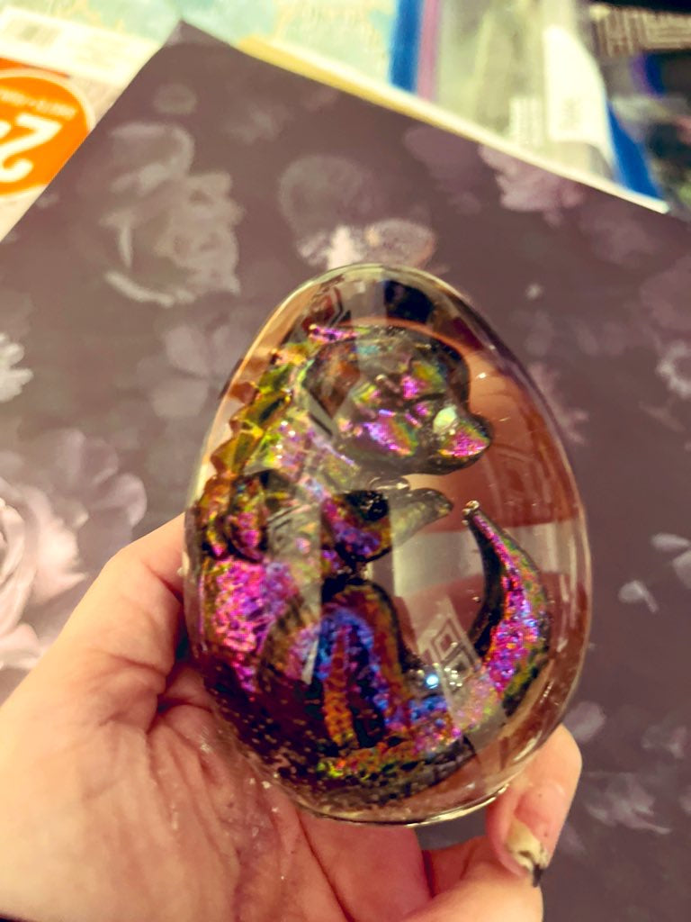 Colorful crystal ball with a dragon design held by a hand against a blurred background
